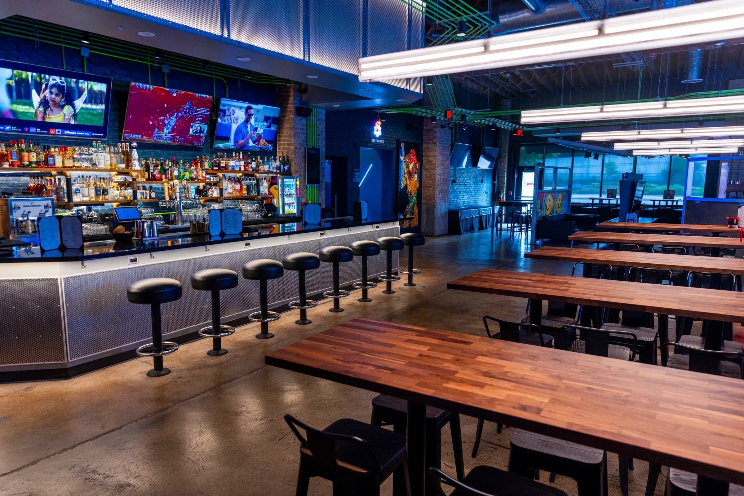 Ignite Arcade's bar and dedicated dining area with high-top tables under the TV wall.