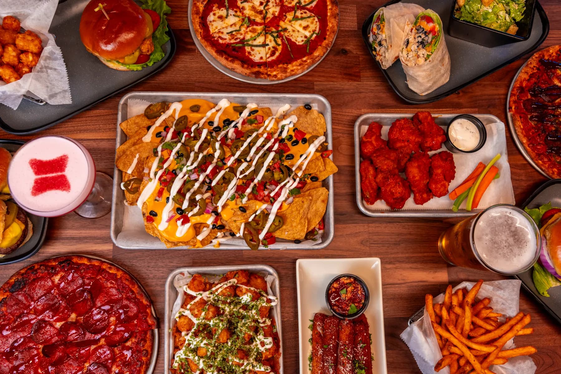 An overhead spread of shareable plates, wings, pizzas, sliders, and fries.