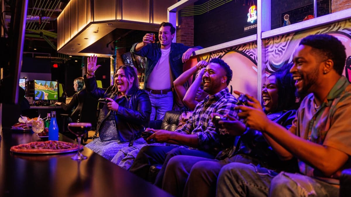 Private console gaming booth with couch seating and a large screen.