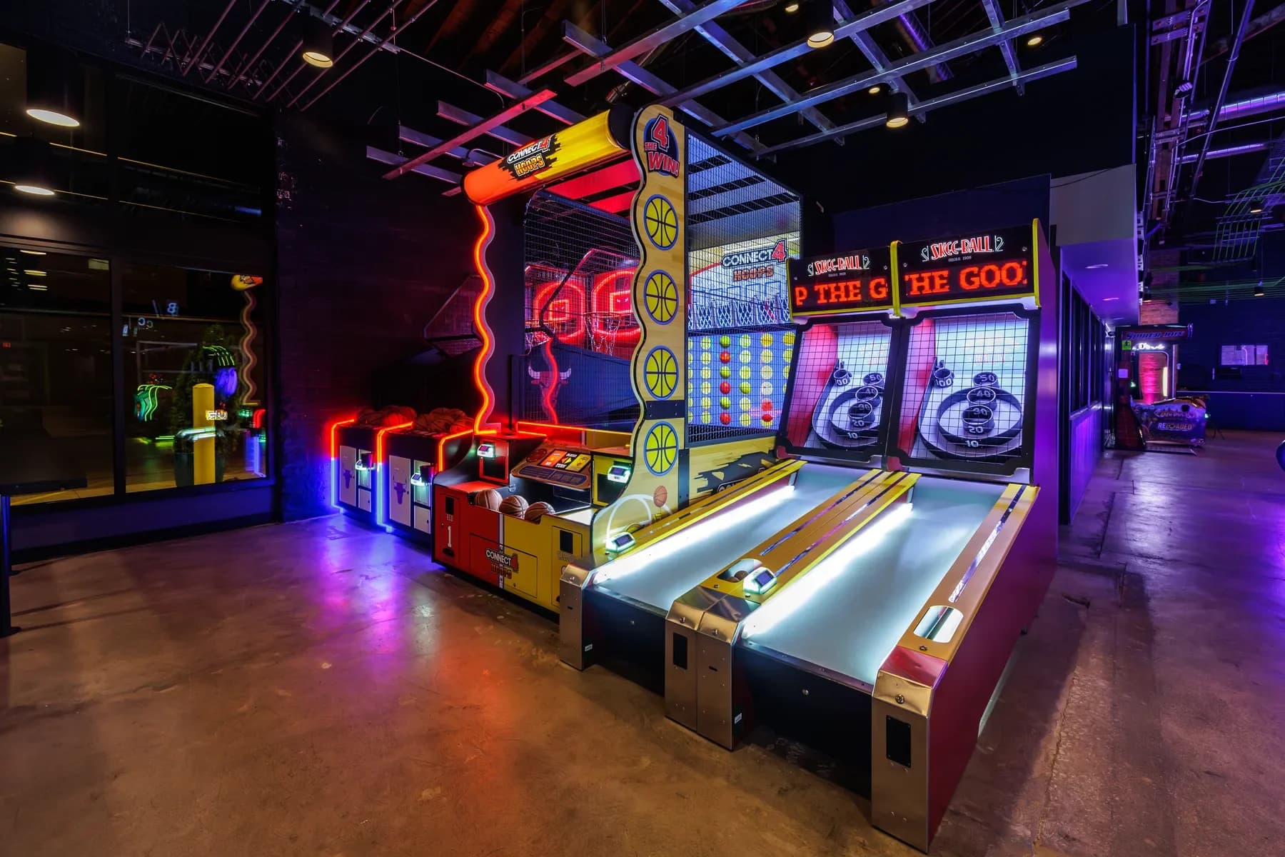 Connect 4 Hoops and Skee-Ball cabinets glowing under arcade lighting at Ignite Arcade.