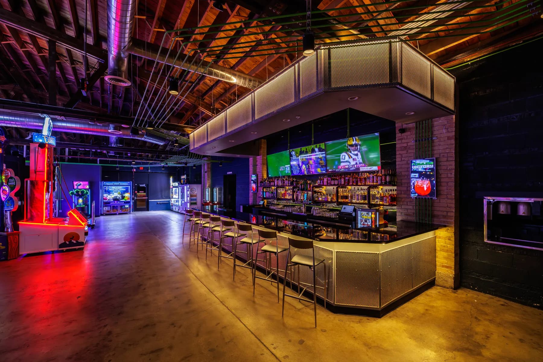 Ignite Arcade's open event floor with a full bar, arcade cabinets, and big-screen TVs.