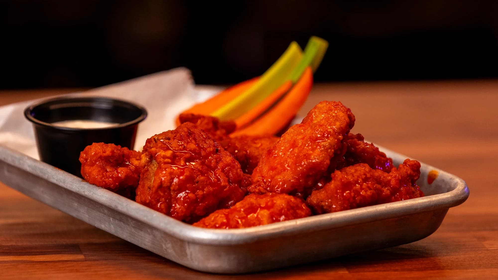Saucy wings with carrots, celery, and ranch on a tray at Ignite Arcade.