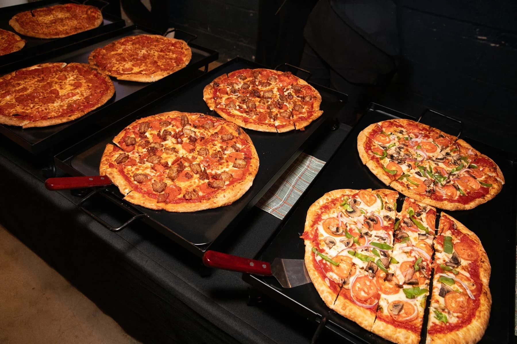 Pepperoni and veggie pizzas on trays ready to serve.