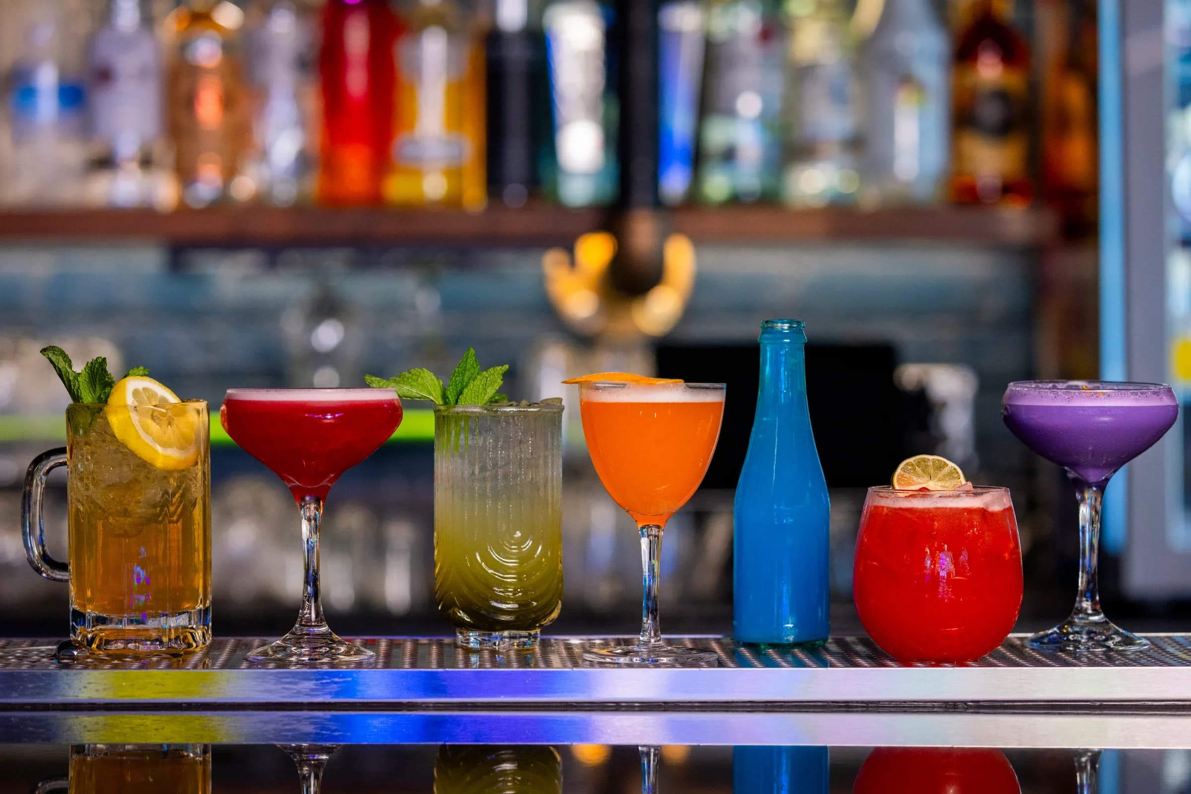 A row of colorful signature cocktails along the Ignite Arcade bar.