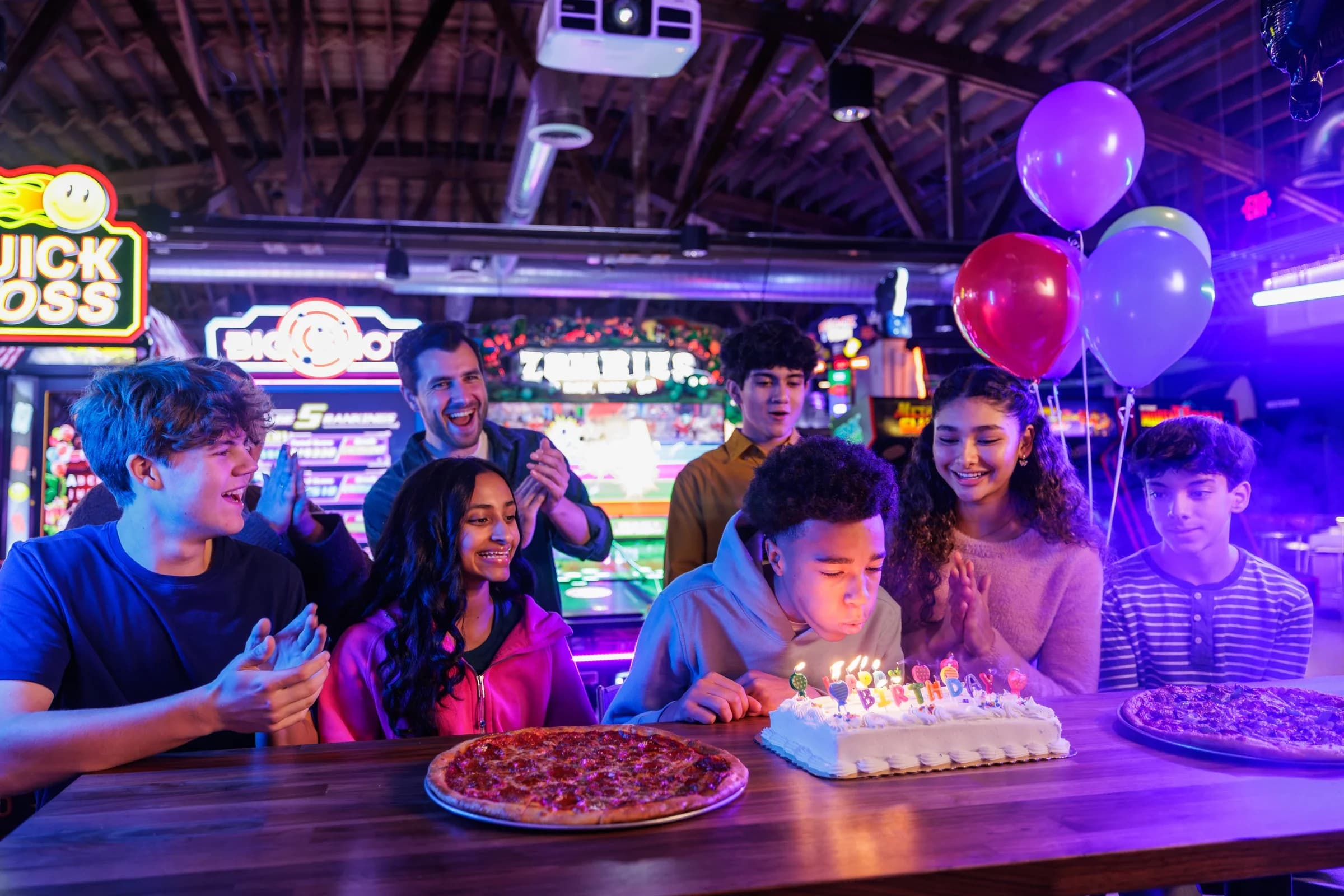 A young boy blowing out the candles on his birthday cake at Ignite Arcade.